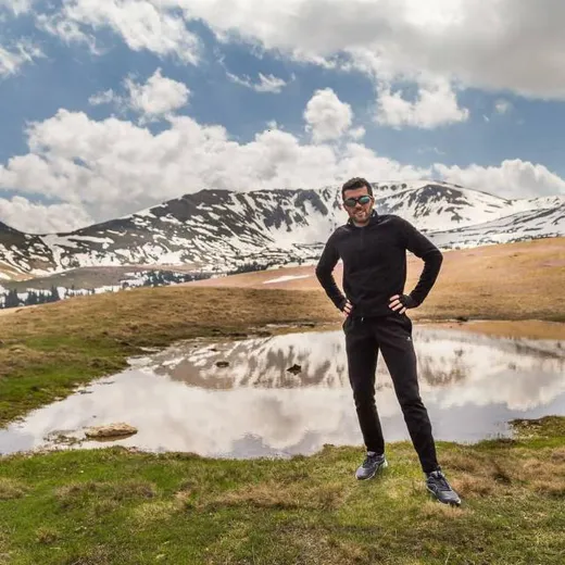 Bogdan standing by an alpine lake, smiling